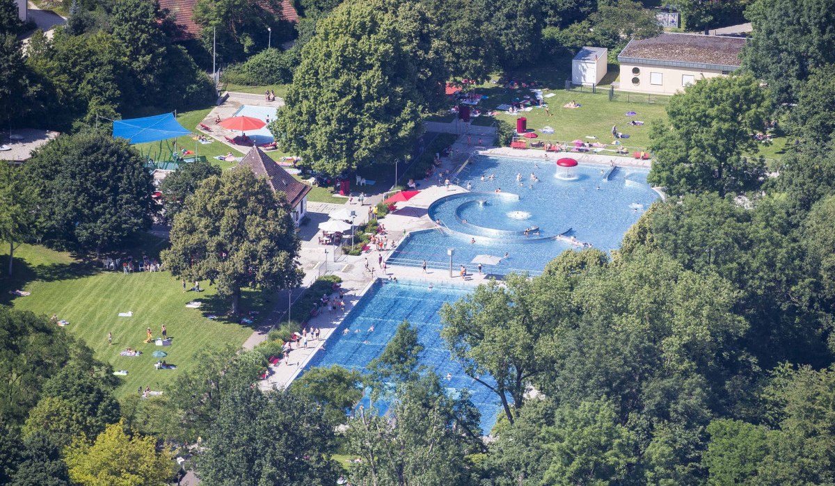 Luftaufnahme des Freibads in Kirchheim unter Teck mit Schwimmbecken, Liegewiese und Bäumen. Menschen entspannen und schwimmen bei sonnigem Wetter., © Schwäbische Alb Tourismusverband e.V.