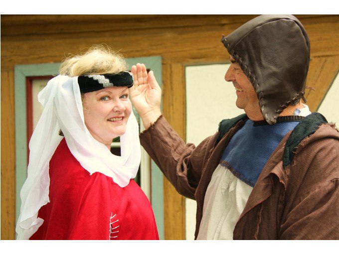 Zwei Personen in mittelalterlicher Kleidung lächeln vor einem Fachwerkhaus. Die Frau trägt ein rotes Gewand, der Mann eine braune Kapuze., © Touristik und Marketing GmbH Zwei Personen in mittelalterlicher Kleidung lächeln vor einem Fachwerkhaus. Die Frau trägt ein rotes Gewand, der Mann eine braune Kapuze., © Touristik und Marketing GmbH