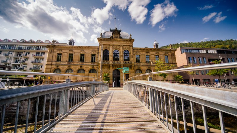 Historisches Geb&auml;ude in Bad Wildbad, Deutschland, mit einer Holzbr&uuml;cke im Vordergrund und blauem Himmel im Hintergrund., &copy; Touristik Bad Wildbad