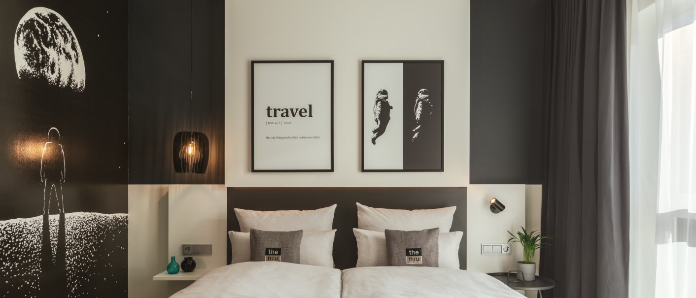 Modernes Hotelzimmer mit Weltraumdekor, Doppelbett, zwei Bildern an der Wand und stilvoller Beleuchtung. Dunkle Vorhänge und minimalistische Einrichtung., © Novum Management GmbH Modernes Hotelzimmer mit Weltraumdekor, Doppelbett, zwei Bildern an der Wand und stilvoller Beleuchtung. Dunkle Vorhänge und minimalistische Einrichtung., © Novum Management GmbH
