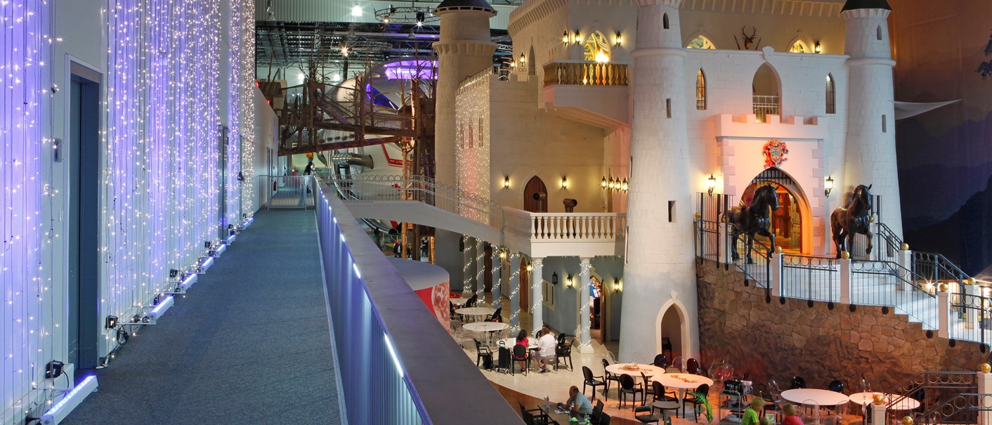 Ein beleuchtetes Märchenschloss im Sensapolis mit Cafébereich und Besuchern. Lichterketten schmücken den Gang., © Sensapolis Sindelfingen