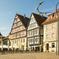 Historische Gebäude am Marktplatz in Schwäbisch Gmünd, darunter Fachwerkhäuser und das Rathaus. Sonnenschirme und leere Tische im Vordergrund., © Stuttgart-Marketing GmbH, Sarah Schmid