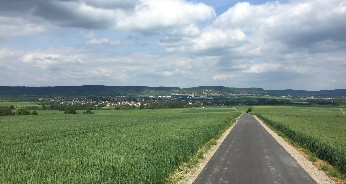 Ein asphaltierter Radweg führt durch grüne Felder in Richtung des Dorfes Gültstein. Der Himmel ist bewölkt, und die Landschaft wirkt friedlich., © www.pro-cycl.de Ein asphaltierter Radweg führt durch grüne Felder in Richtung des Dorfes Gültstein. Der Himmel ist bewölkt, und die Landschaft wirkt friedlich., © www.pro-cycl.de