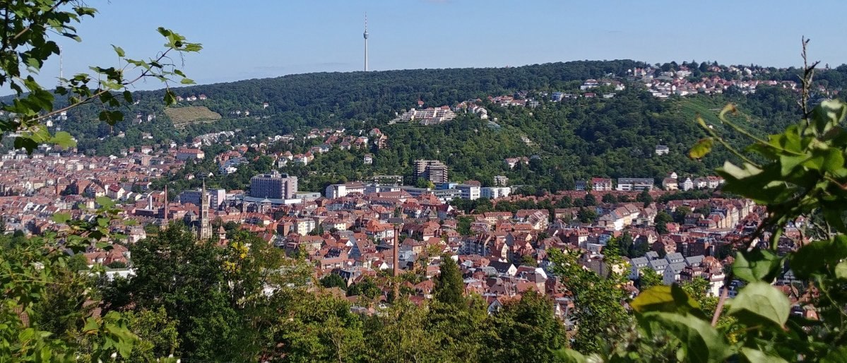 Panoramablick auf Stuttgart mit roten Dächern, grünen Hügeln und dem Fernsehturm im Hintergrund, umgeben von Bäumen., © Stuttgart-Marketing GmbH Panoramablick auf Stuttgart mit roten Dächern, grünen Hügeln und dem Fernsehturm im Hintergrund, umgeben von Bäumen., © Stuttgart-Marketing GmbH