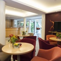 Moderne Hotel-Lobby mit gemütlichen Sesseln, Tischen mit Blumen, einem großen Fernseher und einer Rezeption im Hintergrund., © Hotel Gloria GmbH Restaurant Möhringer Hexle