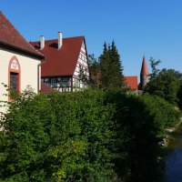 Fachwerkhaus und Kirche mit Turm an einem Flussufer, umgeben von Bäumen und blauem Himmel., © Natur.Nah. Schönbuch & Heckengäu Fachwerkhaus und Kirche mit Turm an einem Flussufer, umgeben von Bäumen und blauem Himmel., © Natur.Nah. Schönbuch & Heckengäu