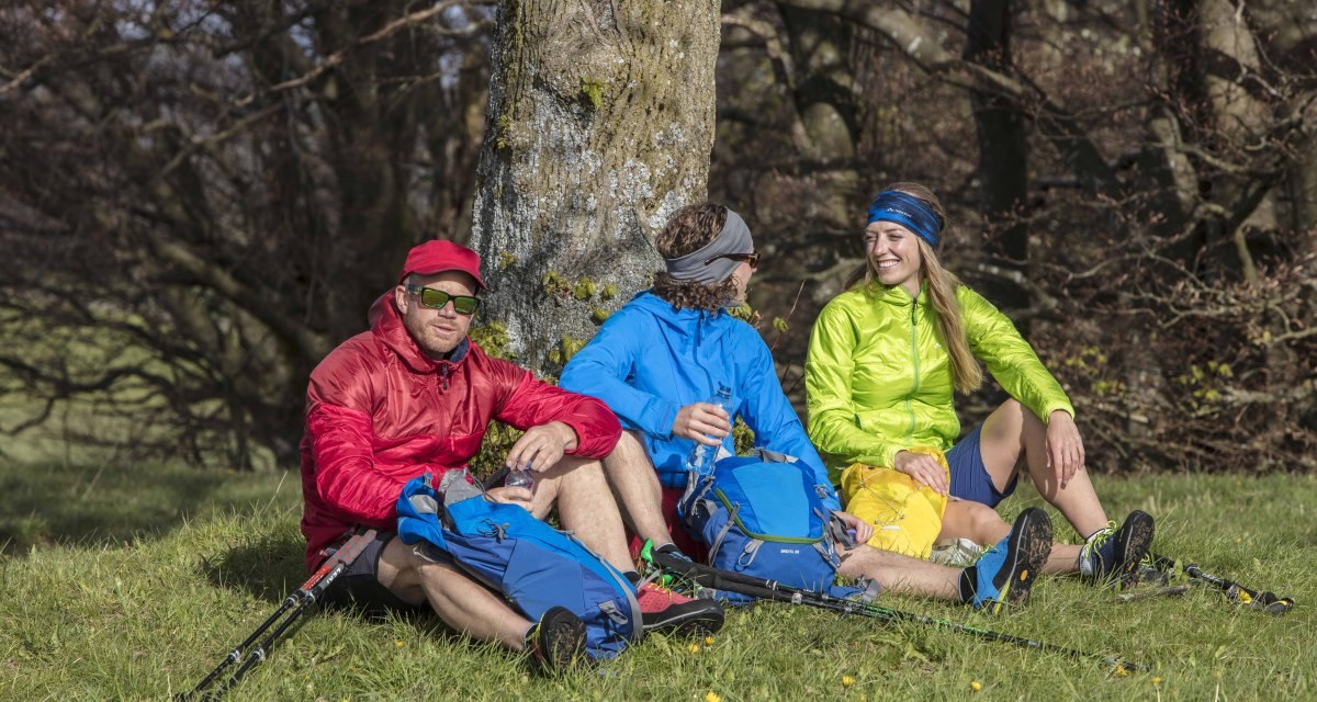 Drei Personen in bunter Outdoor-Kleidung sitzen auf einer Wiese unter einem Baum und machen eine Pause. Sie haben Rucksäcke und Wanderstöcke dabei., © Schwäbische Alb Tourismusverband e.V. Drei Personen in bunter Outdoor-Kleidung sitzen auf einer Wiese unter einem Baum und machen eine Pause. Sie haben Rucksäcke und Wanderstöcke dabei., © Schwäbische Alb Tourismusverband e.V.
