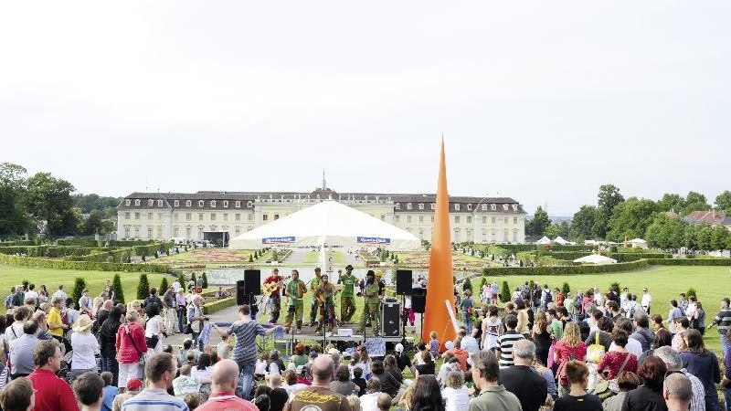 Eine gro&szlig;e Menschenmenge genie&szlig;t ein Stra&szlig;enmusikfestival vor einem historischen Schloss. Eine Band spielt unter einem wei&szlig;en Pavillon., &copy; copyright: Marc Sansone