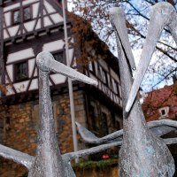 Störche aus Metall vor einem Fachwerkhaus im Städtischen Museum im Storchen Göppingen, umgeben von Bäumen und blauem Himmel., © Stuttgart-Marketing GmbH