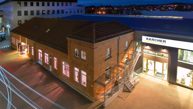 Nachtaufnahme des Kärcher Museums in Winnenden. Ein beleuchtetes Backsteingebäude mit Lichtspuren von Autos im Vordergrund., © SMG Achim Mende Nachtaufnahme des Kärcher Museums in Winnenden. Ein beleuchtetes Backsteingebäude mit Lichtspuren von Autos im Vordergrund., © SMG Achim Mende