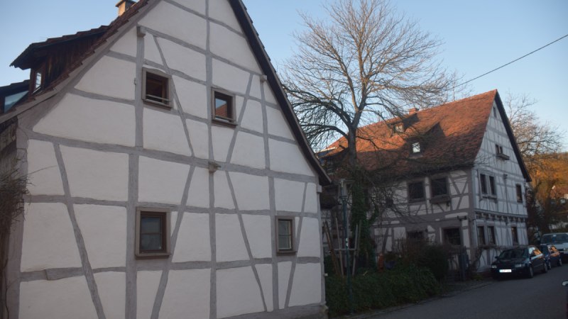 Zwei Fachwerkhäuser in einer ländlichen Straße, umgeben von kahlen Bäumen und parkenden Autos., © Land der 1000 Hügel - Kraichgau-Stromberg Zwei Fachwerkhäuser in einer ländlichen Straße, umgeben von kahlen Bäumen und parkenden Autos., © Land der 1000 Hügel - Kraichgau-Stromberg
