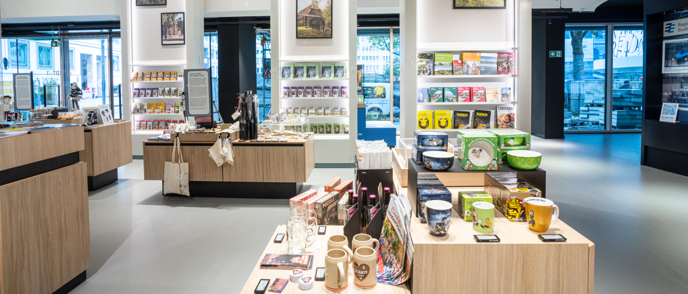 Moderner Souvenirladen mit Holzregalen, gefüllt mit Büchern, Tassen und regionalen Produkten. Große Fenster bieten Blick nach draußen., © Stuttgart-Marketing GmbH, Sarah Schmid