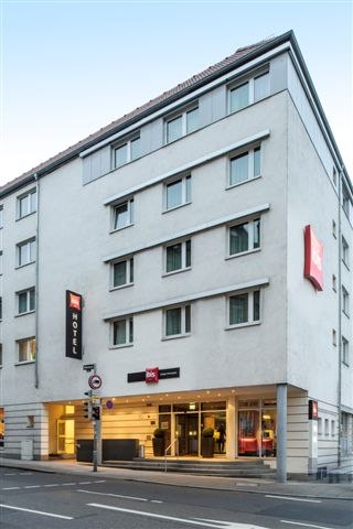 Modernes Hotelgebäude mit mehreren Stockwerken, großen Fenstern und einem Eingang mit Vordach. Hotelname und Logo sind sichtbar., © TOMAS
