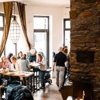 Gemütliches Café mit großen Fenstern, Menschen an Tischen, bunte Kugeln an der Wand und ein Kamin. Warme, einladende Atmosphäre., © Stuttgart-Marketing GmbH, Sarah Schmid