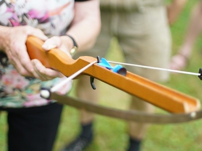 Nahaufnahme einer Person, die eine Armbrust im Freien hält. Die Szene wirkt entspannt und zeigt Freizeitaktivität., © Cool-Tours StattReisen Nahaufnahme einer Person, die eine Armbrust im Freien hält. Die Szene wirkt entspannt und zeigt Freizeitaktivität., © Cool-Tours StattReisen
