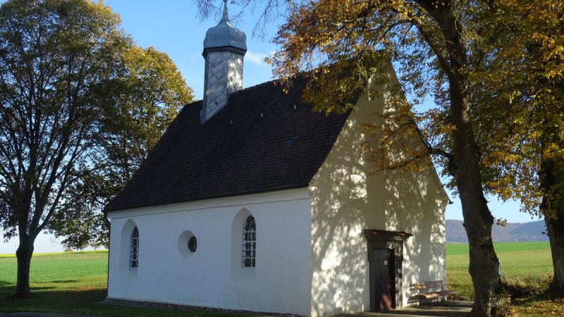 Die Beiswanger Kapelle steht in einer ländlichen Umgebung, umgeben von herbstlichen Bäumen. Die weiße Fassade und der kleine Turm sind gut sichtbar., © Foto: Cornelia Steinbach Die Beiswanger Kapelle steht in einer ländlichen Umgebung, umgeben von herbstlichen Bäumen. Die weiße Fassade und der kleine Turm sind gut sichtbar., © Foto: Cornelia Steinbach