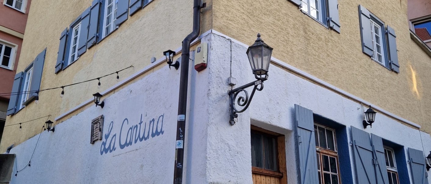 Gelbes Geb&auml;ude mit blauen Fensterl&auml;den und der Aufschrift 'La Cantina'. Historische Architektur mit Laternen und steinernen Details., &copy; cStadtNuertingen