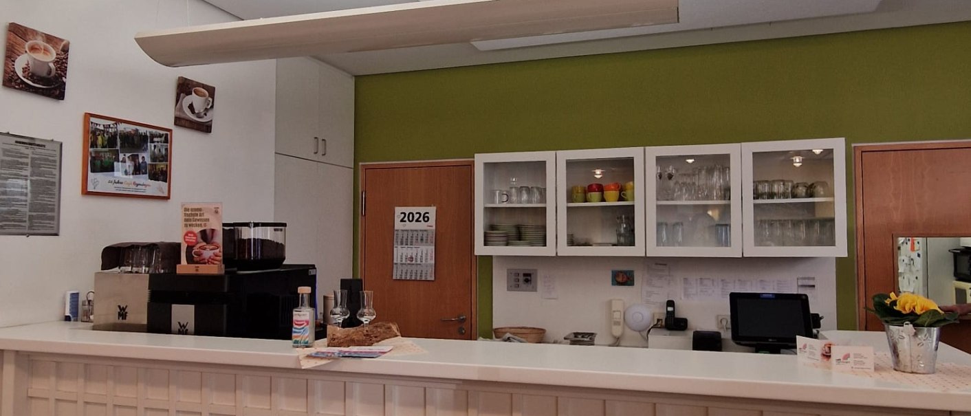 Ein gem&uuml;tliches Caf&eacute; mit einer wei&szlig;en Theke, dekoriert mit Bildern und Tafeln. Im Hintergrund sind Regale mit Geschirr und eine gr&uuml;ne Wand zu sehen., &copy; cStadtNuertingen