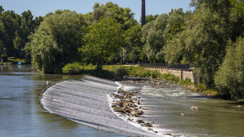 Fischtreppe in N&uuml;rtingen, umgeben von einem Fluss und &uuml;ppiger Vegetation. Ein Schornstein ragt im Hintergrund auf., &copy; SMG Mende