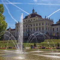 Schloss Ludwigsburg mit prächtigem Garten und Springbrunnen, umgeben von blühenden Blumen. Der Himmel ist blau mit Kondensstreifen., © Tourismus & Events Ludwigsburg
