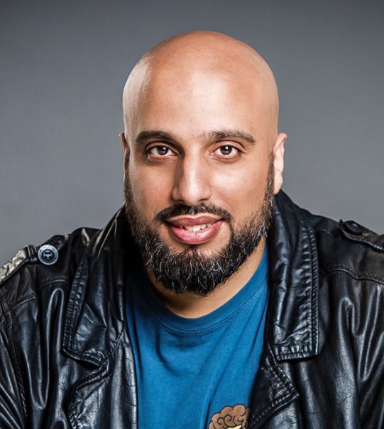 Ein Mann mit Glatze und Bart tr&auml;gt eine Lederjacke und l&auml;chelt in die Kamera. Der Hintergrund ist grau., &copy; Konzertkreis Triangel Compagnia Compostelli e.V.