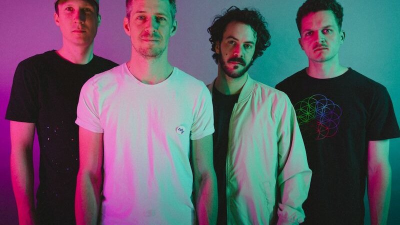 Vier M&auml;nner posieren vor einem farbigen Hintergrund, beleuchtet in rosa und gr&uuml;nem Licht. Sie tragen l&auml;ssige Kleidung., &copy; Stadthalle Leonberg