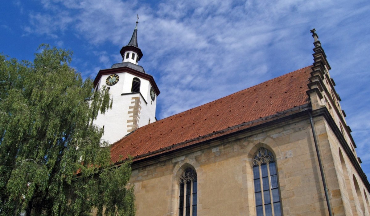 Kirchturm mit Uhr und rotem Dach, flankiert von einem Baum, vor blauem Himmel mit Wolken., © Natur.Nah. Schönbuch & Heckengäu Kirchturm mit Uhr und rotem Dach, flankiert von einem Baum, vor blauem Himmel mit Wolken., © Natur.Nah. Schönbuch & Heckengäu