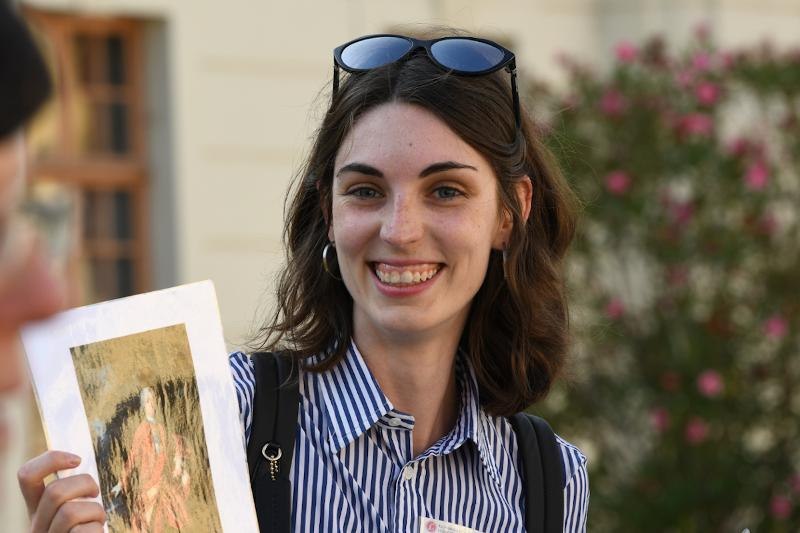 Frau mit gestreiftem Hemd und Sonnenbrille auf dem Kopf h&auml;lt ein Bild in der Hand, l&auml;chelnd vor unscharfem Hintergrund., &copy; &copy; G&uuml;nter Kreft