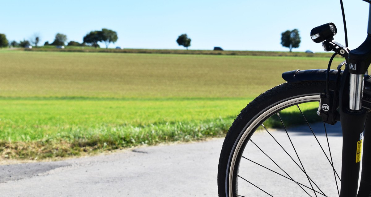 Fahrradvorderrad auf einem ländlichen Weg, im Hintergrund grüne Felder und Bäume unter klarem Himmel., © Stadtmarketing Böblingen e.V. Fahrradvorderrad auf einem ländlichen Weg, im Hintergrund grüne Felder und Bäume unter klarem Himmel., © Stadtmarketing Böblingen e.V.
