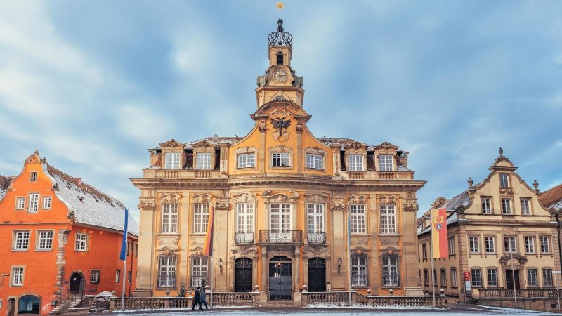 Das Rathaus von Schwäbisch Hall im Winter, mit schneebedeckten Dächern und einem klaren blauen Himmel. Die Architektur ist barock und prächtig verziert., © Stadt Schwäbisch Hall - Michael Kühneisen Das Rathaus von Schwäbisch Hall im Winter, mit schneebedeckten Dächern und einem klaren blauen Himmel. Die Architektur ist barock und prächtig verziert., © Stadt Schwäbisch Hall - Michael Kühneisen