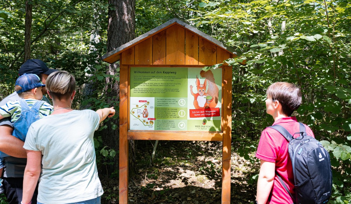 Drei Personen betrachten ein Informationsschild im Wald. Das Schild zeigt eine Karte und ein Eichhörnchen als Wegweiser für den Keppiweg., © Stadtmarketing Weil der Stadt Drei Personen betrachten ein Informationsschild im Wald. Das Schild zeigt eine Karte und ein Eichhörnchen als Wegweiser für den Keppiweg., © Stadtmarketing Weil der Stadt