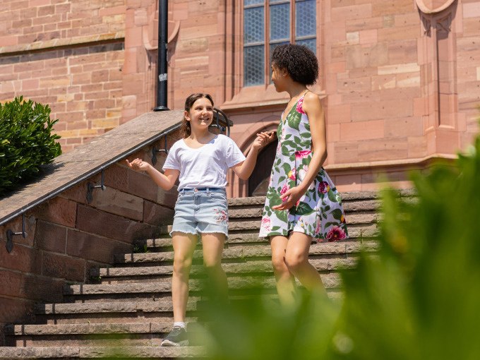 Zwei Frauen gehen l&auml;chelnd eine Steintreppe hinunter, umgeben von gr&uuml;nen B&uuml;schen und einem historischen Geb&auml;ude im Hintergrund., &copy; Stadtverwaltung Weil der Stadt