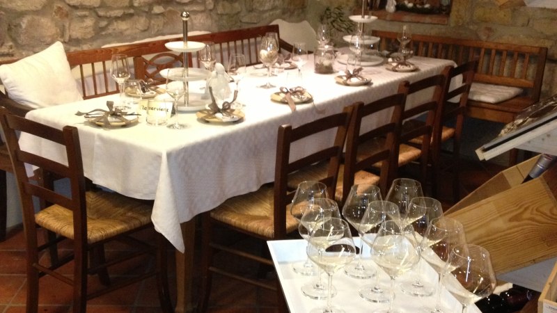 Ein rustikales Restaurant mit einem gedeckten Tisch, umgeben von Steinwänden. Weinflaschen und Gläser sind dekorativ angeordnet., © StadtNuertingen Ein rustikales Restaurant mit einem gedeckten Tisch, umgeben von Steinwänden. Weinflaschen und Gläser sind dekorativ angeordnet., © StadtNuertingen