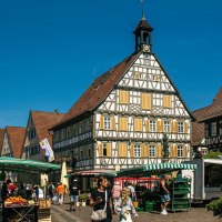 Der Marktplatz in Winnenden zeigt Fachwerkh&auml;user und Marktst&auml;nde unter einem klaren blauen Himmel. Menschen schlendern und kaufen ein., &copy; Stuttgart-Marketing GmbH, Sarah Schmid