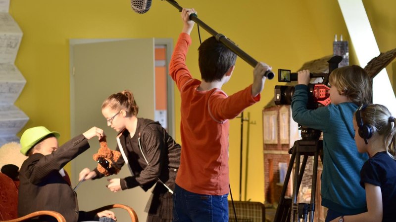 Kinder drehen einen Film mit Kamera und Mikrofon in einem Raum. Ein Kind hält ein Plüschtier, während andere filmen und den Ton aufnehmen., © Kinderfilmhaus Ludwigsburg