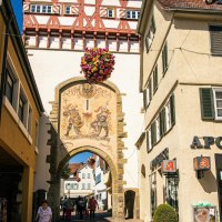 Das Stadttor von Bietigheim-Bissingen mit Fachwerk und Wandmalerei, umgeben von Geschäften wie einer Apotheke und einem Bekleidungsgeschäft., © Stuttgart-Marketing GmbH, Sarah Schmid Das Stadttor von Bietigheim-Bissingen mit Fachwerk und Wandmalerei, umgeben von Geschäften wie einer Apotheke und einem Bekleidungsgeschäft., © Stuttgart-Marketing GmbH, Sarah Schmid