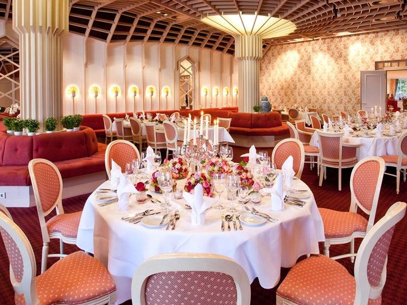 Elegantes Restaurant mit runden, festlich gedeckten Tischen, roten Polstermöbeln und stilvoller Beleuchtung., © Mokni's Palais Hotel & Spa Elegantes Restaurant mit runden, festlich gedeckten Tischen, roten Polstermöbeln und stilvoller Beleuchtung., © Mokni's Palais Hotel & Spa