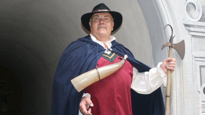 Brustbild des Gaildorfer Nachtw&auml;chters mit rotem Wams, blauem Umhang, schwarzem Hut und umgh&auml;ngtem Horn; in der linken Hand eine Hellebarde haltend., &copy; Petra Natzkowski