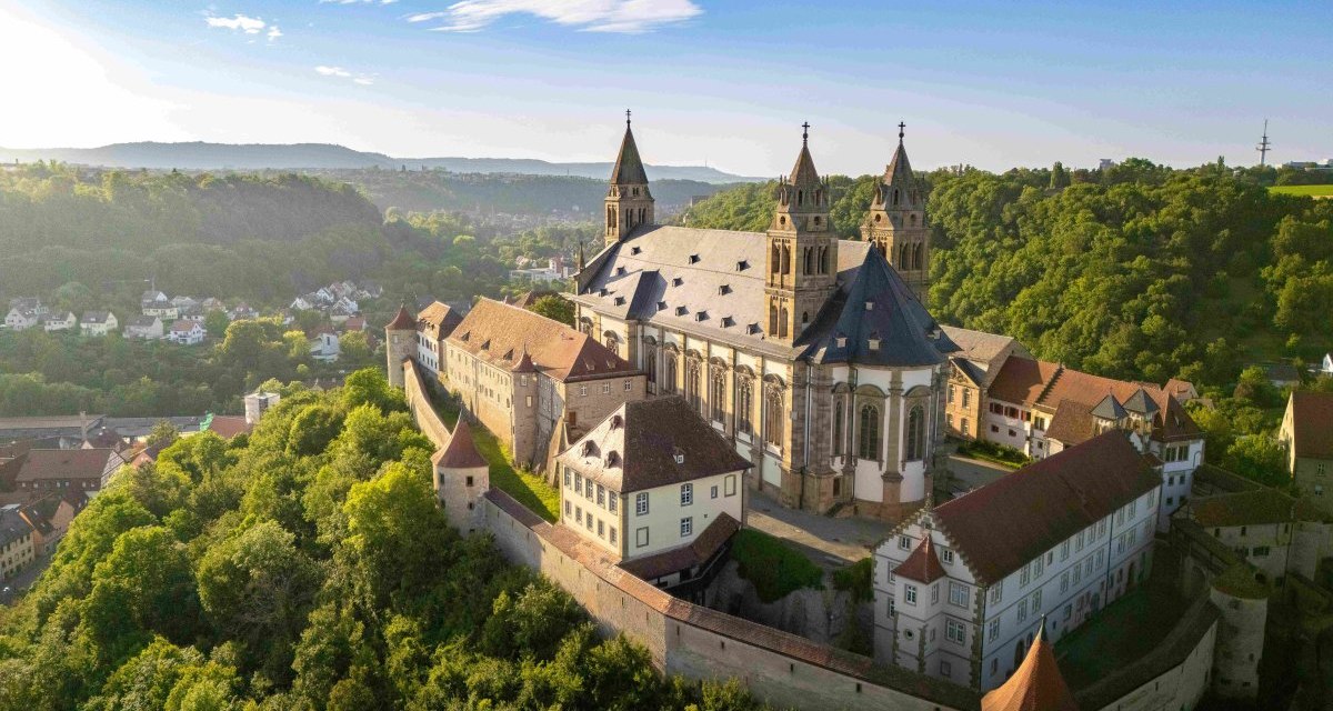 Luftaufnahme der Gro&szlig;comburg in Schw&auml;bisch Hall, umgeben von gr&uuml;nen W&auml;ldern und H&uuml;geln unter blauem Himmel., &copy; Michael K&uuml;hneisen