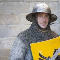 Ein Mann in mittelalterlicher R&uuml;stung mit Kettenhemd und Helm h&auml;lt ein gelbes Schild mit schwarzem Adler vor einer Steinmauer., &copy; Esslinger Stadtmarketing &amp; Tourismus GmbH