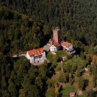 Luftaufnahme der Burg Liebenzell im Schwarzwald, umgeben von dichtem Wald. Die Burg hat einen markanten Turm und mehrere Gebäude mit roten Dächern., © Stuttgart-Marketing GmbH Luftaufnahme der Burg Liebenzell im Schwarzwald, umgeben von dichtem Wald. Die Burg hat einen markanten Turm und mehrere Gebäude mit roten Dächern., © Stuttgart-Marketing GmbH