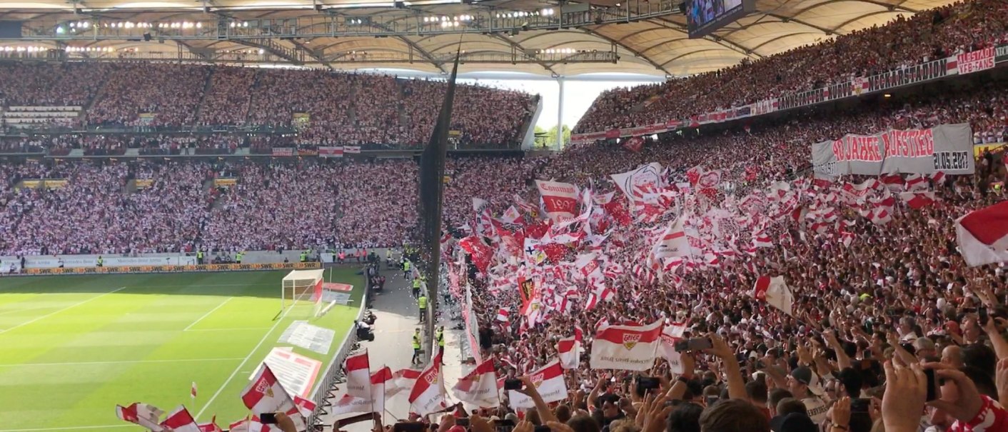 Blick in die Cannstatter Kurve der Mercedes-Benz Arena Stuttgart. Fans schwenken rot-wei&szlig;e Fahnen und halten Banner hoch. Die Trib&uuml;nen sind voll besetzt., &copy; Stuttgart-Marketing GmbH