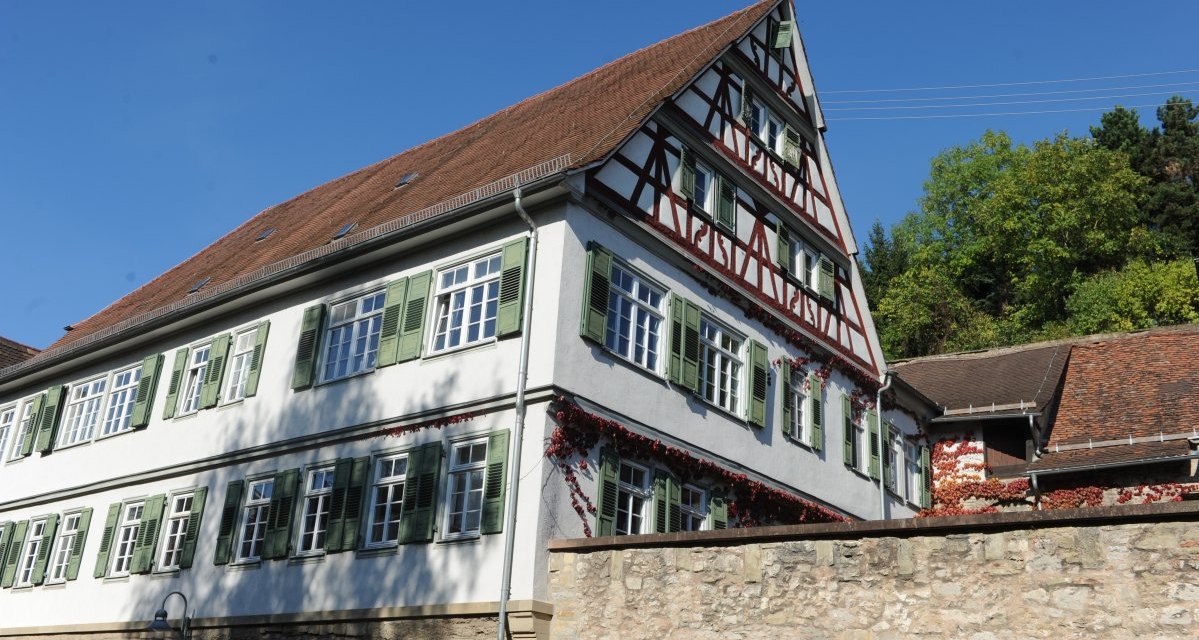 Fachwerkhaus mit grünem Fensterläden und rotem Dach, umgeben von einer Steinmauer, vor einem klaren blauen Himmel., © Land der 1000 Hügel - Kraichgau-Stromberg Fachwerkhaus mit grünem Fensterläden und rotem Dach, umgeben von einer Steinmauer, vor einem klaren blauen Himmel., © Land der 1000 Hügel - Kraichgau-Stromberg