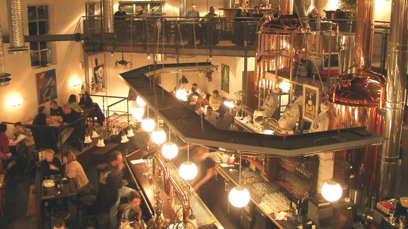 Belebtes Restaurant mit Braukesseln, G&auml;sten an Tischen und einer Bar. Industrielles Design mit warmem Licht und moderner Einrichtung., &copy; Kesselhaus, Schorndorf