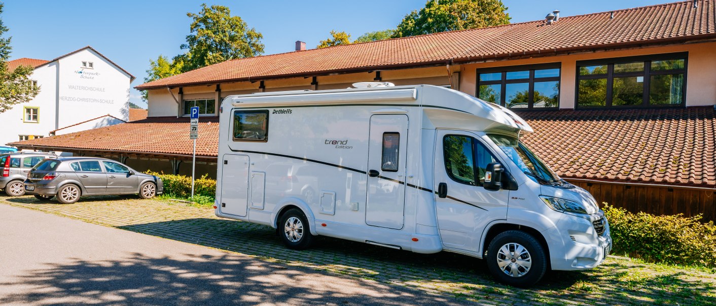 Ein Wohnmobil steht auf einem Parkplatz vor einem Gebäude mit rotem Ziegeldach und blauen Himmel im Hintergrund., © Stuttgart-Marketing GmbH, Thomas Niedermüller Ein Wohnmobil steht auf einem Parkplatz vor einem Gebäude mit rotem Ziegeldach und blauen Himmel im Hintergrund., © Stuttgart-Marketing GmbH, Thomas Niedermüller