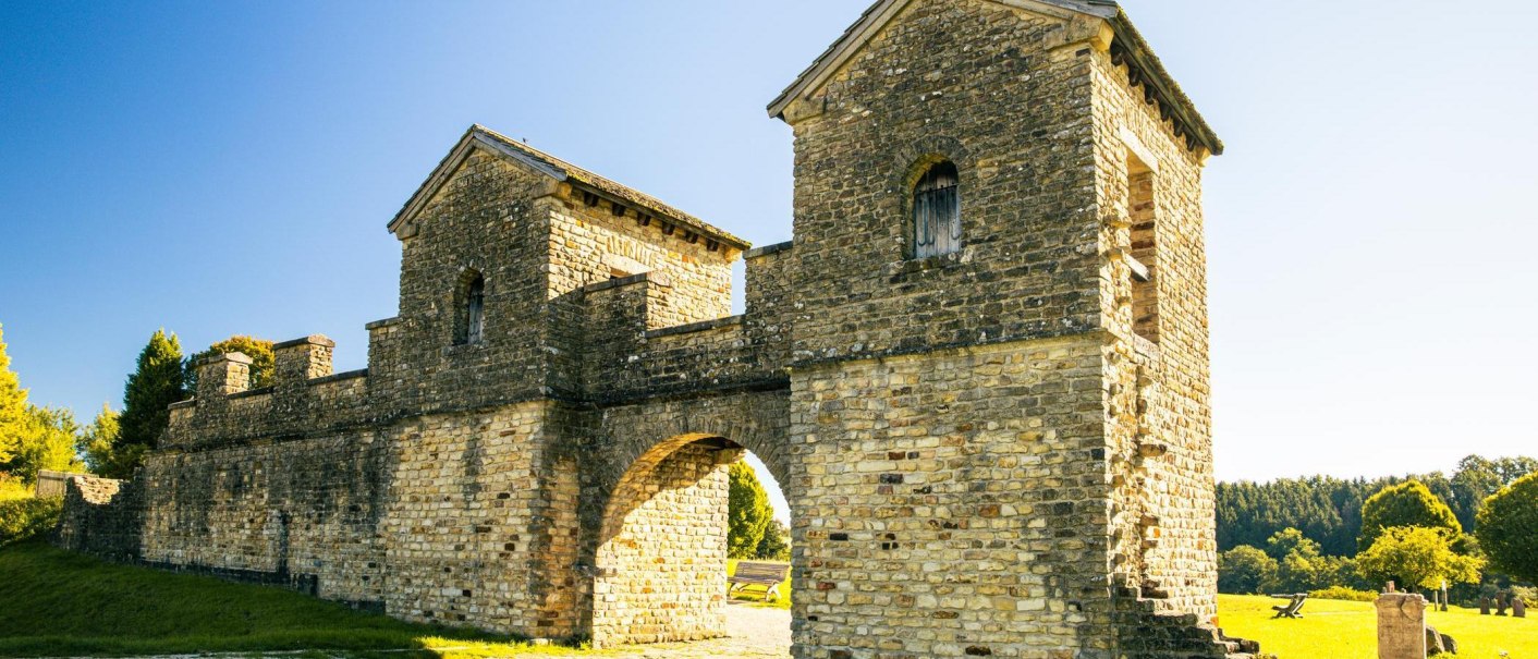 Das Ostkastell in Welzheim zeigt ein gut erhaltenes römisches Tor aus Stein, umgeben von grüner Landschaft und strahlend blauem Himmel., © Stuttgart-Marketing GmbH, Sarah Schmid
