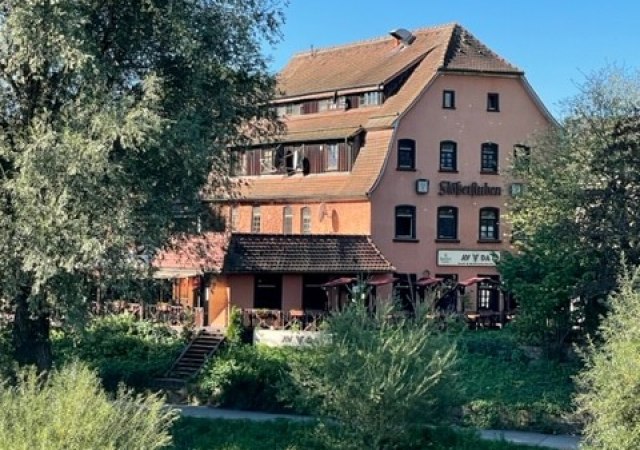Ein mehrst&ouml;ckiges Geb&auml;ude mit rotem Dach und dem Schriftzug "Stiftskeller". Es ist von B&auml;umen und Gr&uuml;nfl&auml;chen umgeben, der Himmel ist klar und blau., &copy; Avada