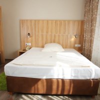 Ein gemütliches Einzelzimmer mit einem Bett, Holzmöbeln und floralen Vorhängen. Ein grüner Teppich liegt auf dem Boden., © Hotel Reinhardtshof Garni Ein gemütliches Einzelzimmer mit einem Bett, Holzmöbeln und floralen Vorhängen. Ein grüner Teppich liegt auf dem Boden., © Hotel Reinhardtshof Garni