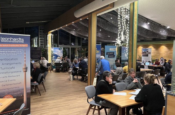 Gäste sitzen in einem stilvollen Restaurant mit großen Fenstern und Lichterketten. Ein Banner des Restaurants Leonhardts ist sichtbar., © SWR Media Services GmbH / SWR Fernsehturm Stuttgart