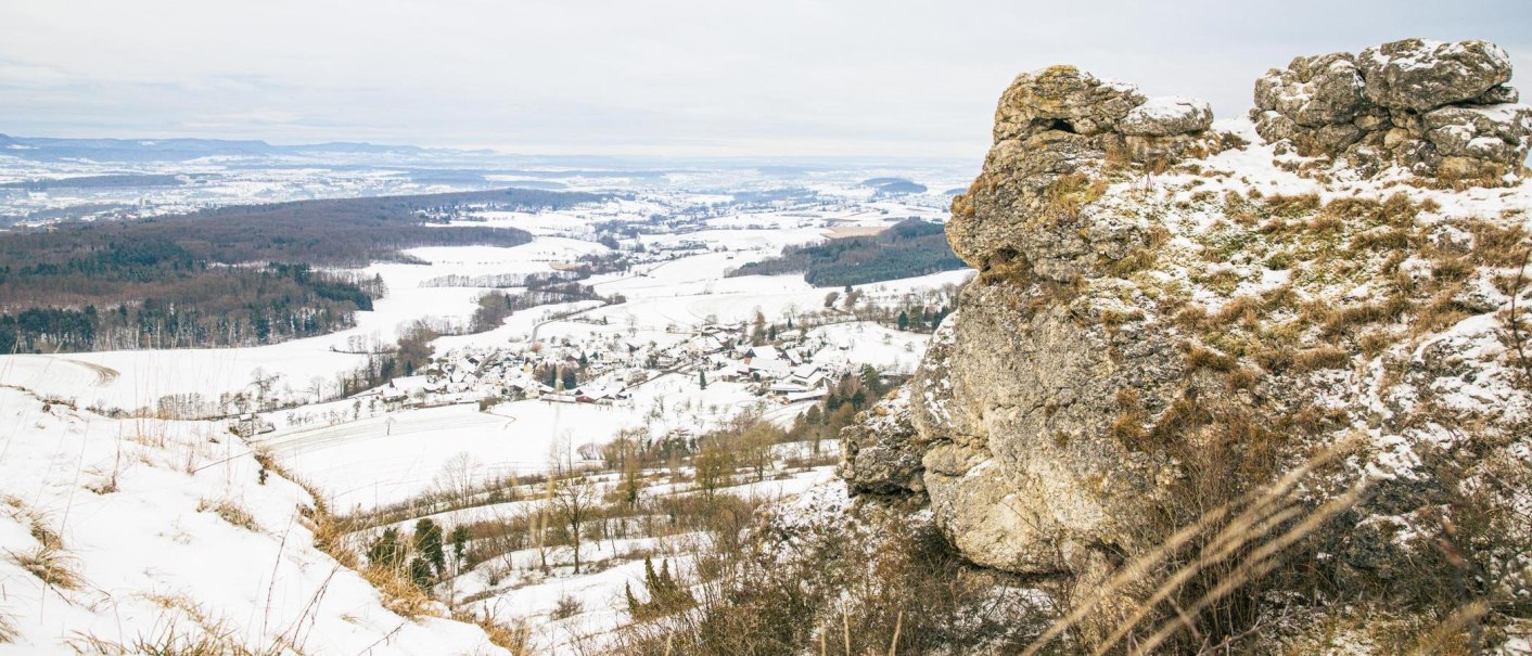 Ein winterlicher Ausblick von einem Felsen auf eine schneebedeckte Landschaft mit Feldern und W&auml;ldern im Hintergrund., &copy; Stuttgart-Marketing GmbH, Sarah Schmid